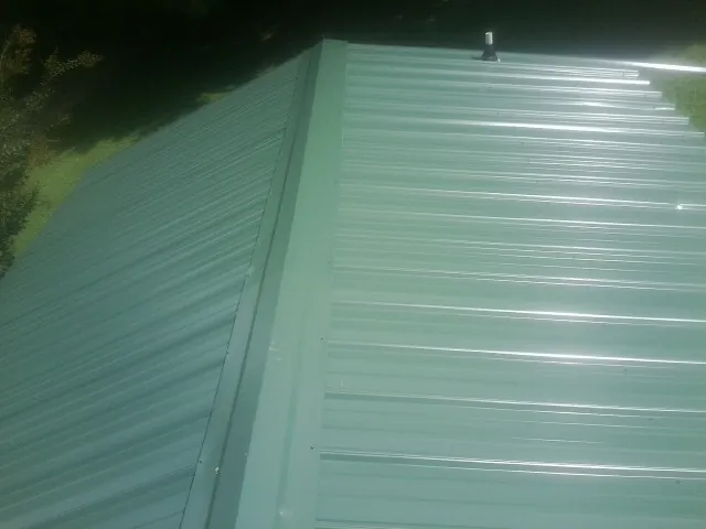 New green metal panels meeting at the ridge of a roof — Flat Roof Repair work by our crew in Hobart